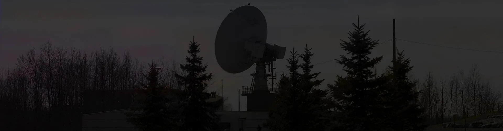 A silhouette of a radio telescope at dark